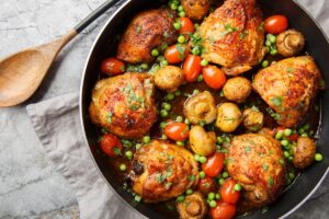 Pulpe de pui cu legume în cratiță și o lingură de lemn