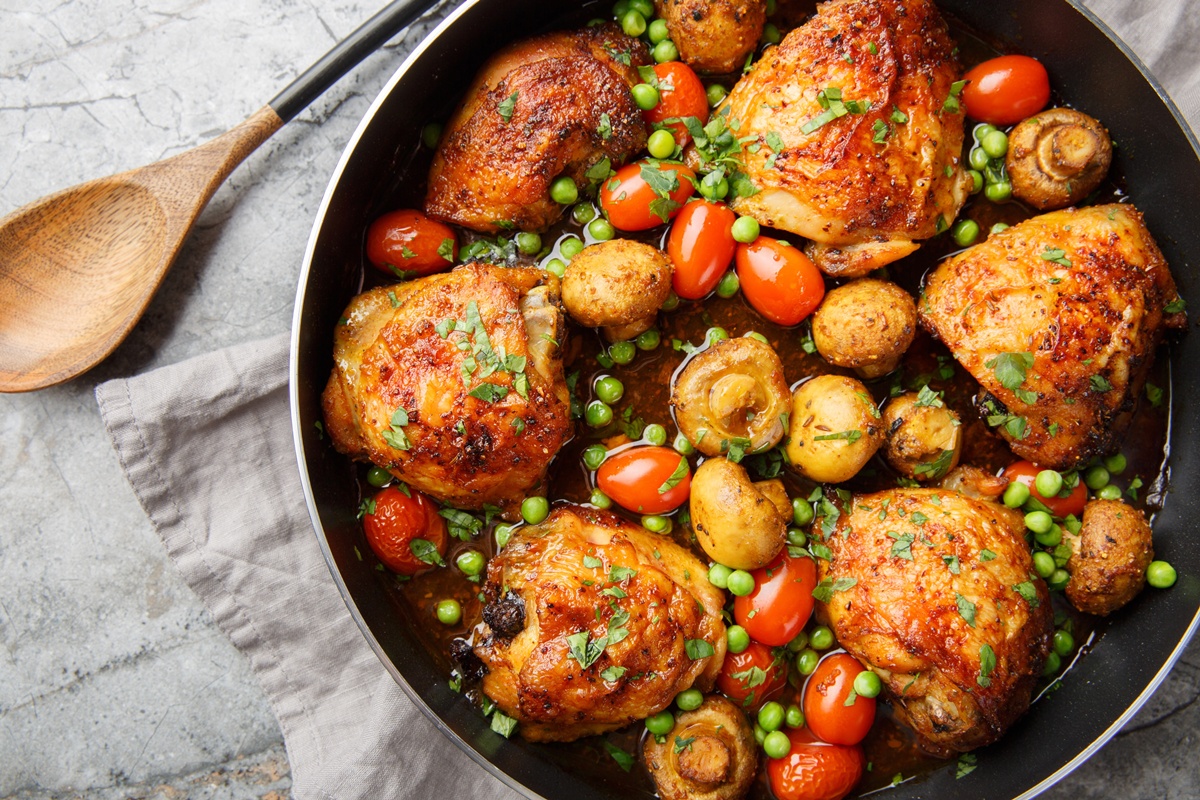 Pulpe de pui cu legume în cratiță și o lingură de lemn