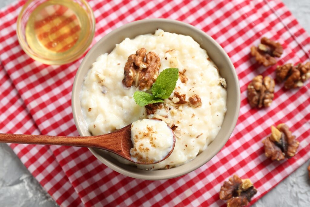 Orez de post cu lapte de cocos în bol cu linguriță, decorat cu nuci și mentă