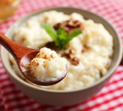 Orez cremos cu lapte de cocos în bol cu linguriță, decorat cu nuci și mentă