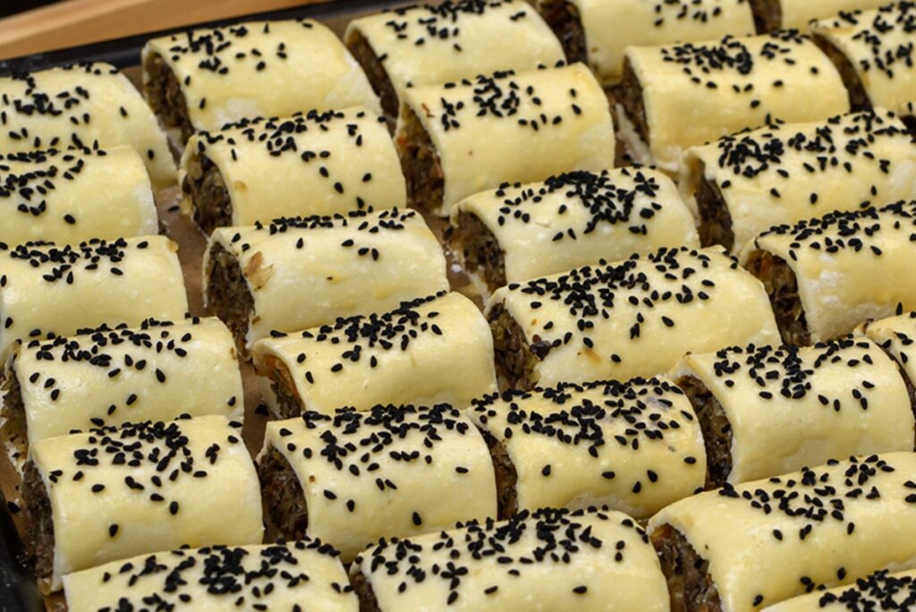 Pateuri cu varză călită și ciuperci, presărate cu susan negru, înainte de coacere