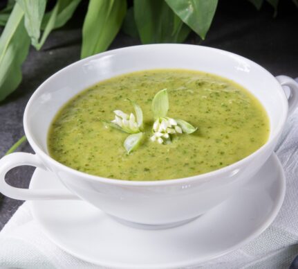 Supă cremă de leurdă în bol, decorată cu floare de leurdă