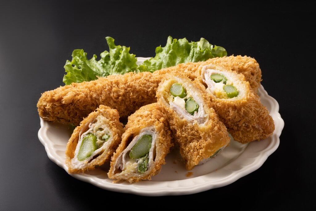 Cordon bleu cu sparanghel în interior pe o farfurie cu salată verde