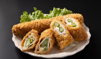 Cordon bleu cu sparanghel în interior pe o farfurie cu salată verde