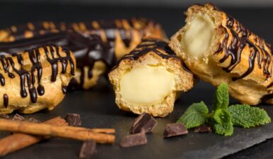 Eclere cu cremă de vanilie și glazură de ciocolată, unul secționat