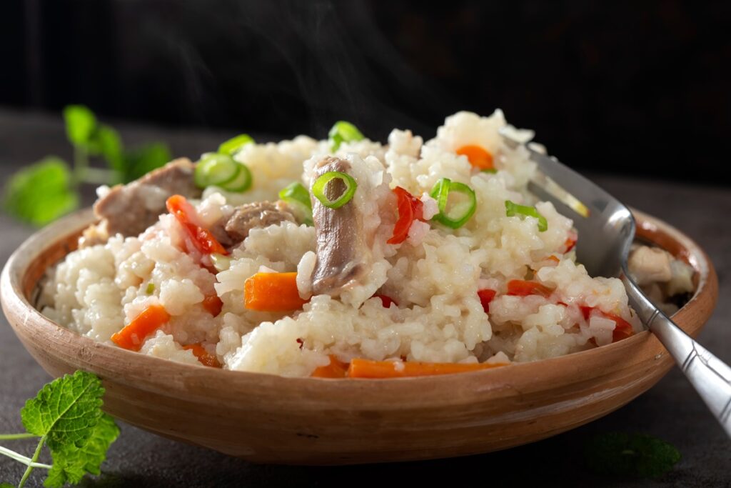 Orez cu pui și legume în bol cu furculiță