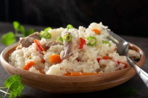 Orez cu pui și legume în bol cu furculiță