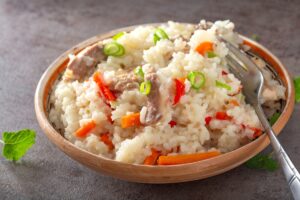 Pilaf cu pui și legume în bol cu furculiță