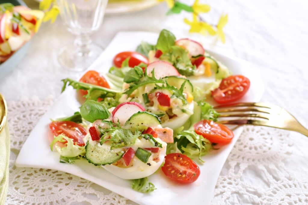 Salată cu ouă umplute și legume crocante pw un platou alb cu furculiță