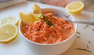 Salată de morcovi cu dressing de iaurt în bol, decorată cu lămâie