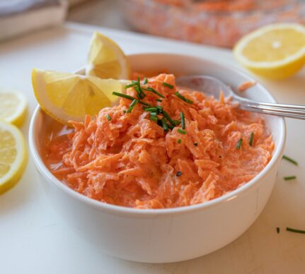 Salată de morcovi cu dressing de iaurt în bol, decorată cu lămâie