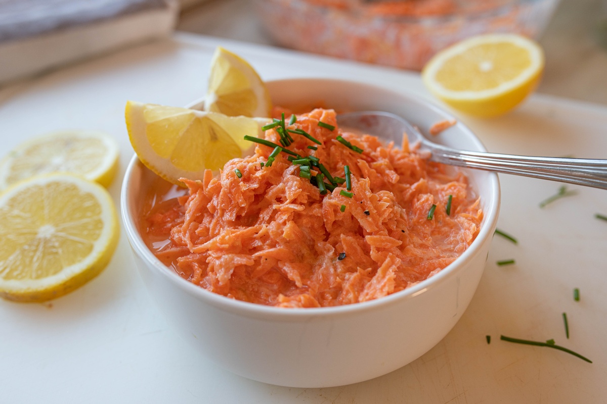 Salată de morcovi cu dressing de iaurt în bol, decorată cu lămâie
