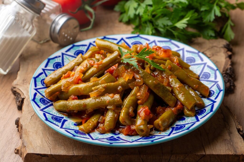 Fasole verde cu ceapă caramelizată și roșii în farfurie