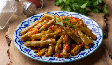Fasole verde cu ceapă caramelizată și roșii în farfurie