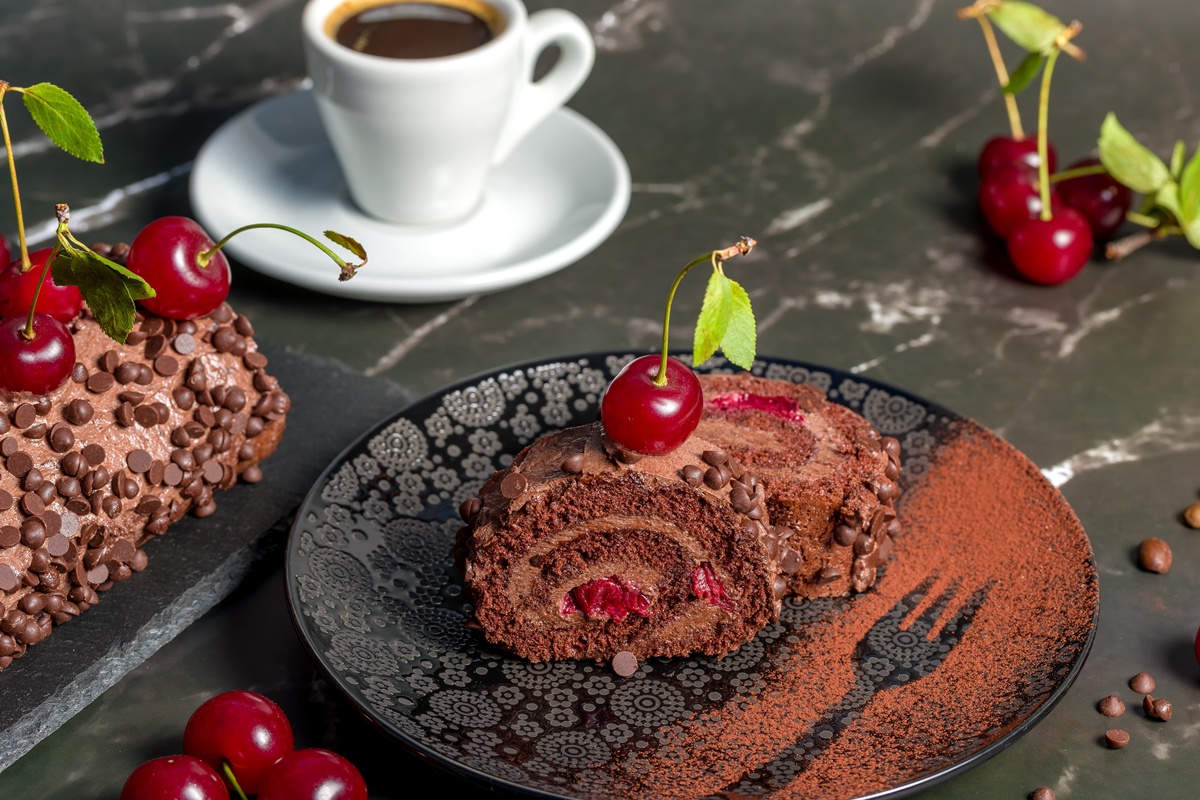Porții de ruladă pe farfurie, o ceașcă de cafea și rulada pe platou