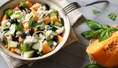 Salată cu pepene galben, castraveți și brânză feta în bol cu furculiță