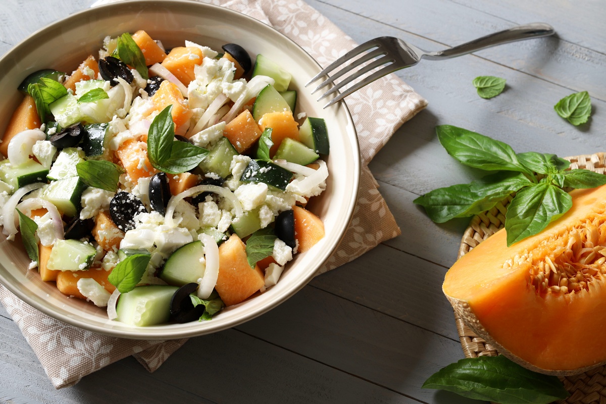 Salată cu pepene galben, castraveți și brânză feta în bol cu furculiță