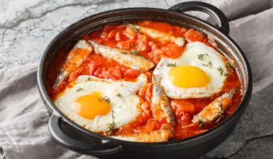 Sardine în sos de roșii cu ouă ochiuri în vas de fontă