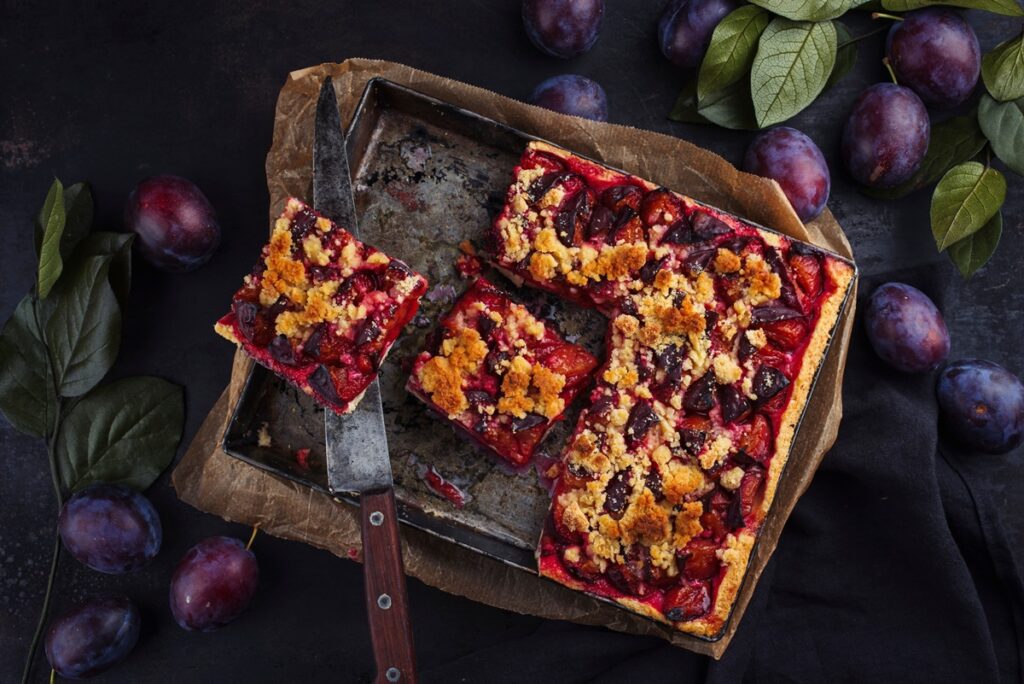 Porții de prăjitură fragedă cu prune și crumble în tavă