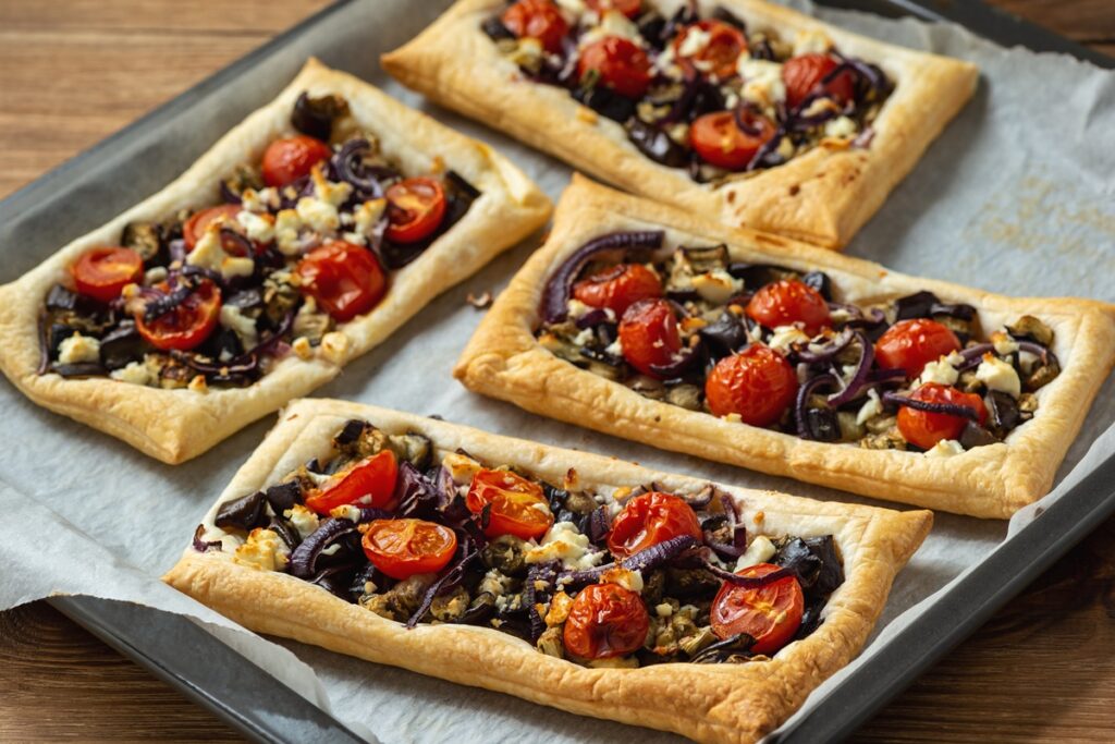 Patru tarte din foietaj cu vinete, roșii cherry, ceapă roșie și brânză feta
